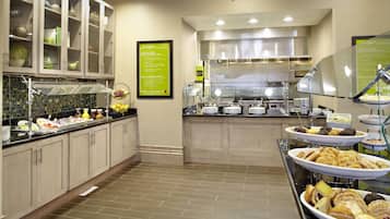 A buffet area with various food stations, including a fruit bowl and a selection of pastries.