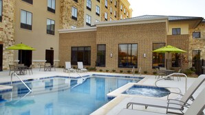 Hotel com piscina, área de estar externa e fachada de tijolos.
