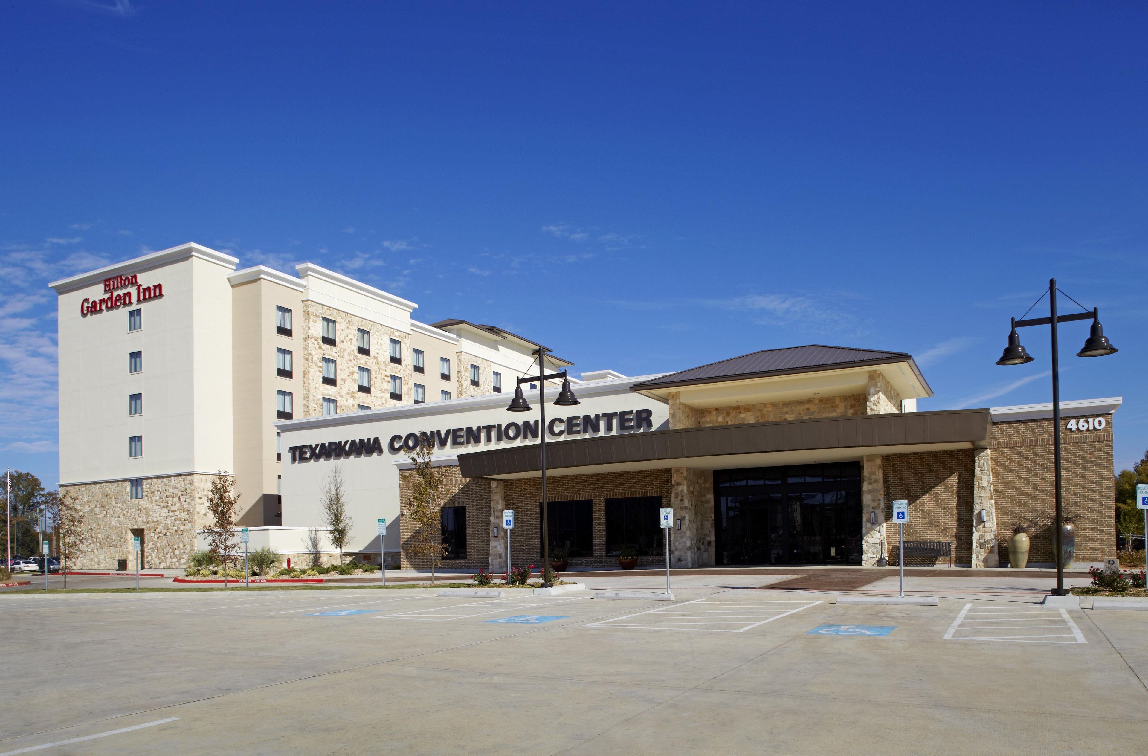 A hotel with a 'Hilton Garden Inn' sign, a 'Texarkana Convention Center' entrance, and a parking lot with handicapped parking spaces.