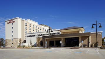 A hotel with a 'Hilton Garden Inn' sign, a 'Texarkana Convention Center' entrance, and a parking lot with handicapped parking spaces.