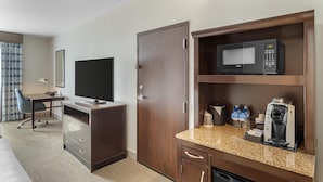 Une chambre d’hôtel équipée d’un bureau, d’une télévision, d’un four à micro-ondes, d’une machine à café et d’armoires de rangement.