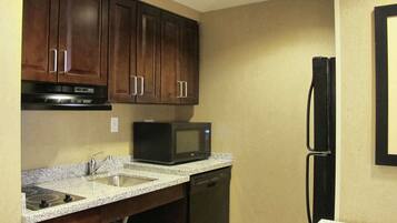 A kitchen with dark wooden cabinets, a built-in microwave, a dishwasher, and a refrigerator.