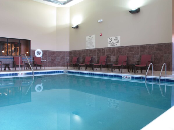 Una piscina con sillas de descanso y señales de seguridad.