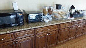A kitchen with a microwave, toaster, and various food items on the counter. - Red Roof Inn Needles (Needles)