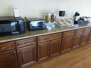 A kitchen with a microwave, toaster, and various food items on the counter. - Red Roof Inn Needles (Needles)