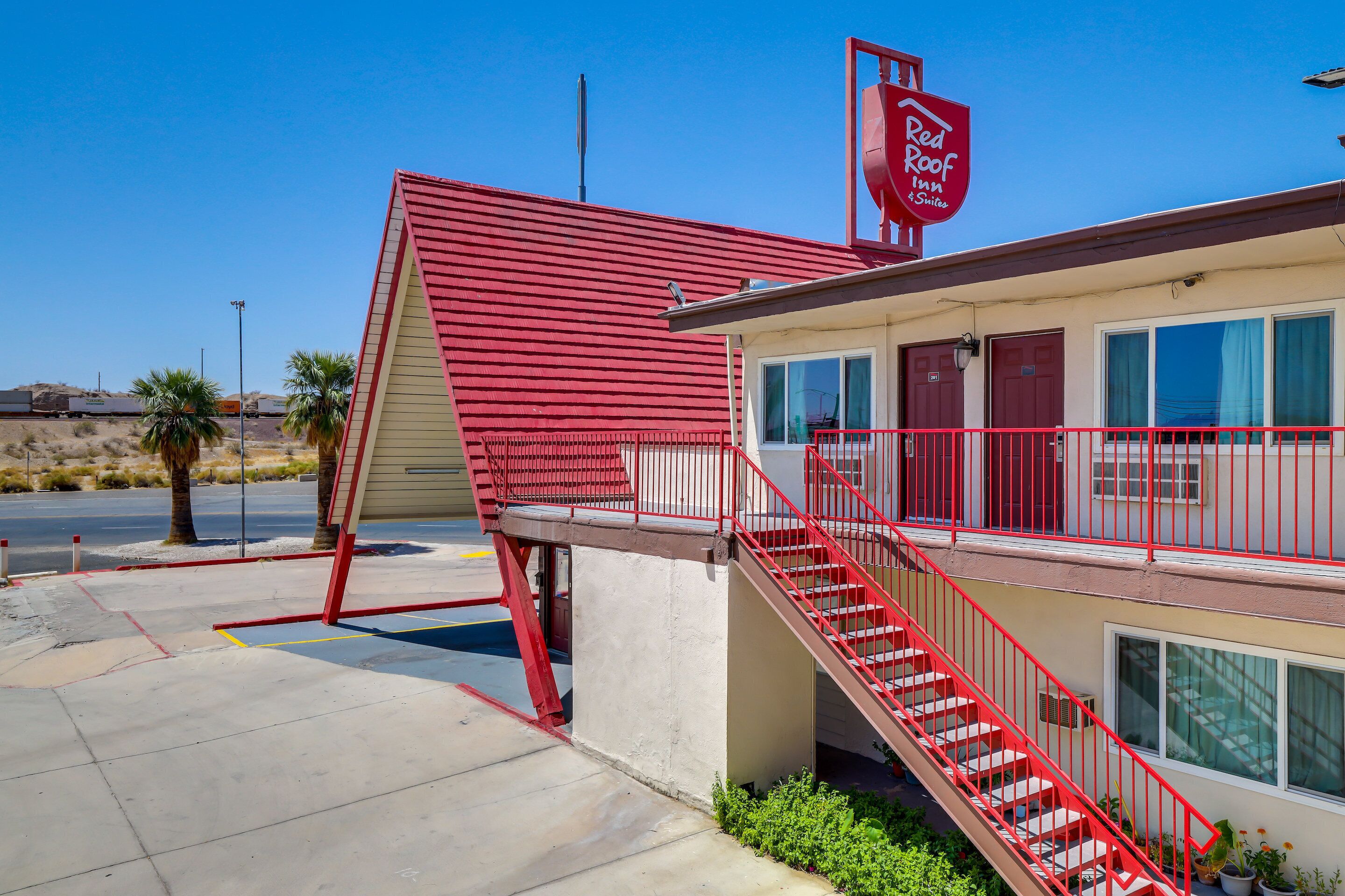 A Red Roof Inn with a red exterior, a red staircase, and a clear blue sky.