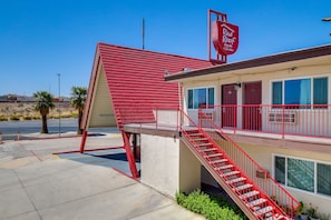 A Red Roof Inn with a red exterior, a staircase, and a parking lot. - Red Roof Inn Needles (Needles)