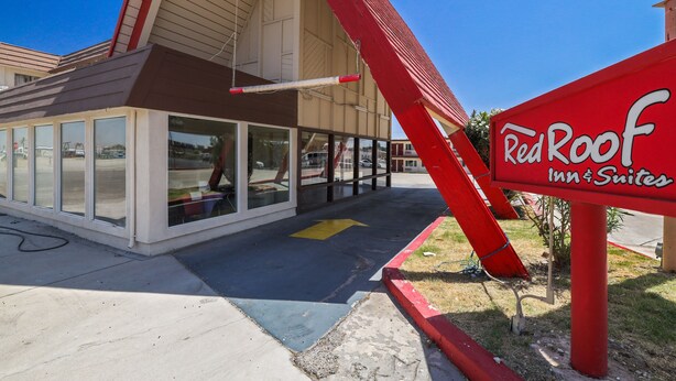 A Red Roof Inn & Suites with a large glass facade, a red awning, and a clear sky. - Red Roof Inn Needles (Needles)