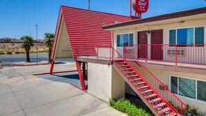 A Red Roof Inn with a red exterior, a staircase, and a parking lot. - Red Roof Inn Needles (Needles)