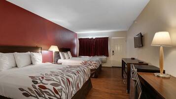 Una habitación de hotel con dos camas, un escritorio, una silla, un televisor y una ventana con cortinas.