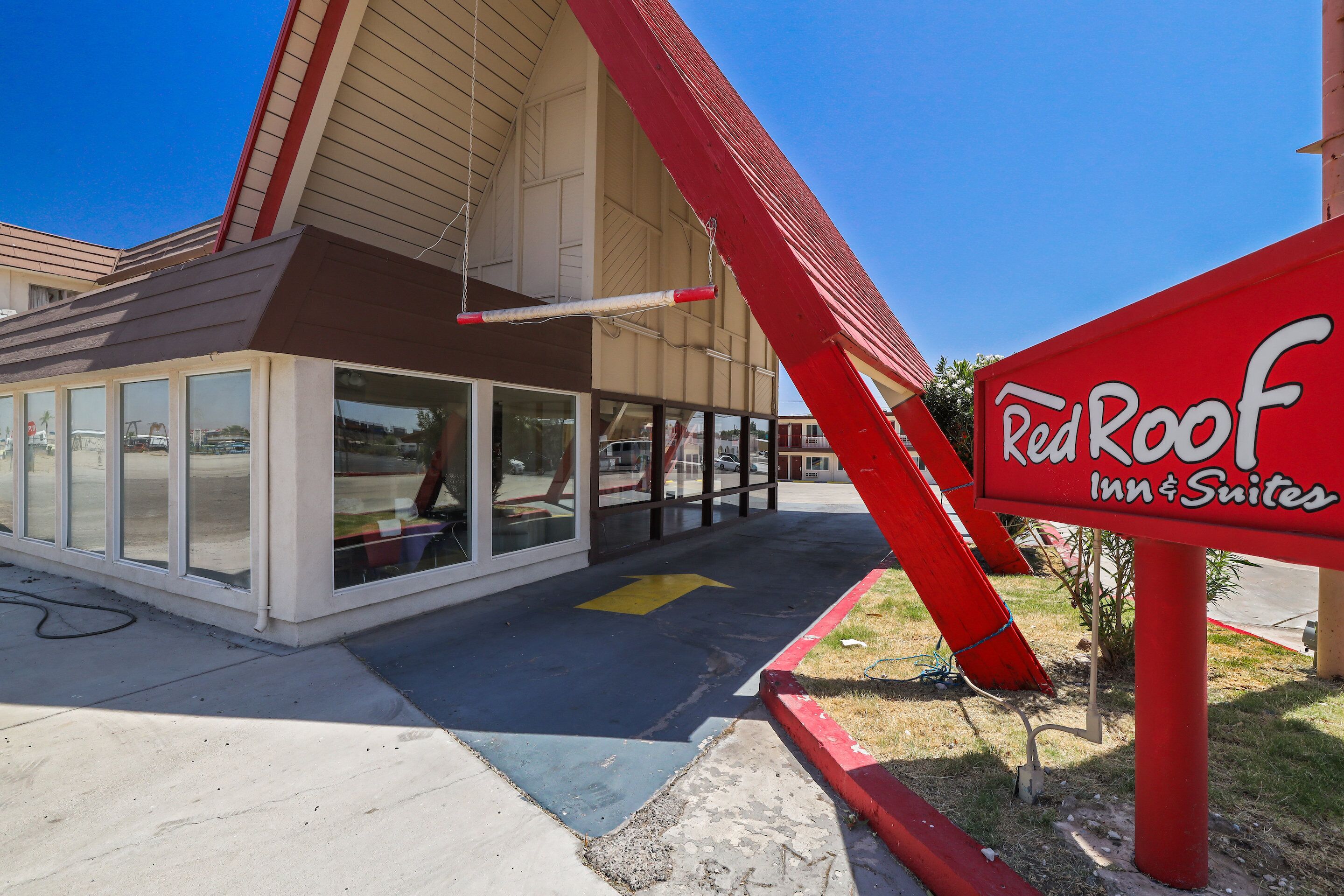 The exterior of Red Roof Inn & Suites with a clear sky, large windows, and a red sign.