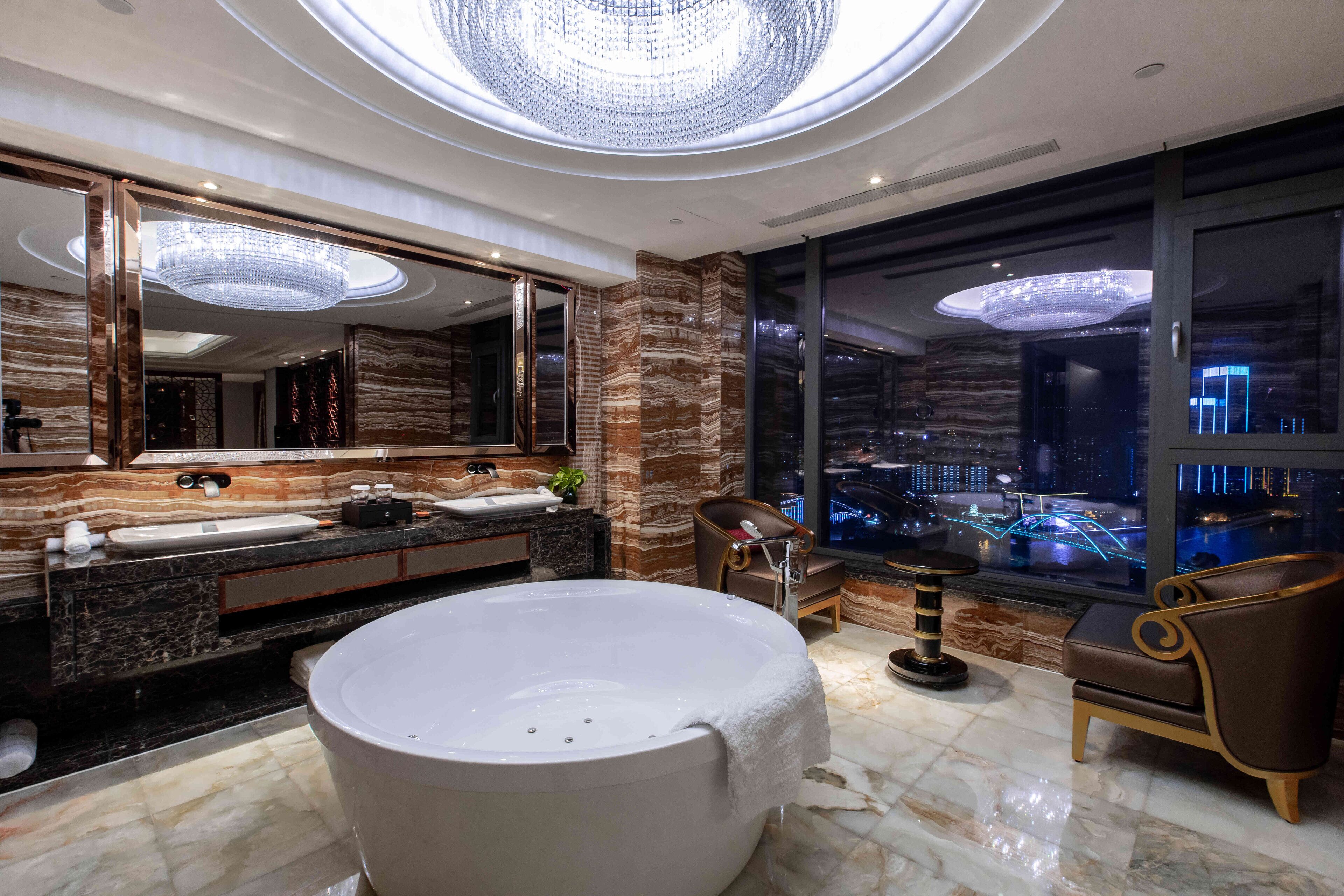 A luxurious bathroom with a large bathtub, dual sinks, and a large mirror.