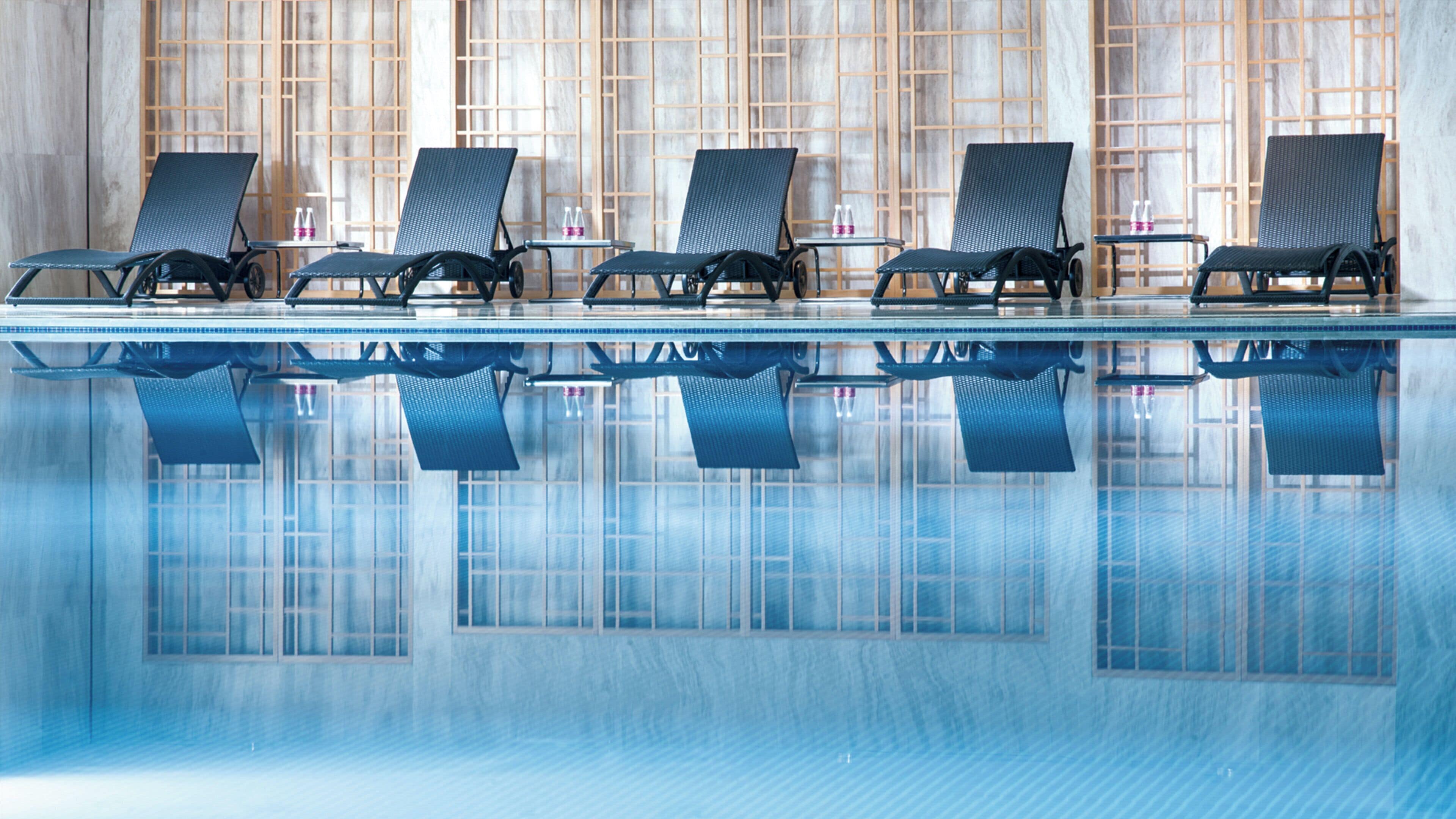 A poolside area with lounge chairs and a tiled floor.