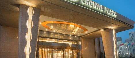 A hotel entrance with a prominent sign reading 'CROWNE PLAZA' and a modern design featuring large columns and a glass facade.