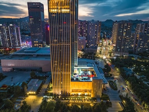 Un edificio moderno de gran altura, rodeado de otros edificios altos y una calle con mucho tráfico.