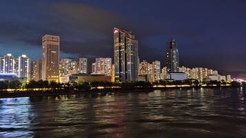 A nighttime cityscape with illuminated buildings along a waterfront.