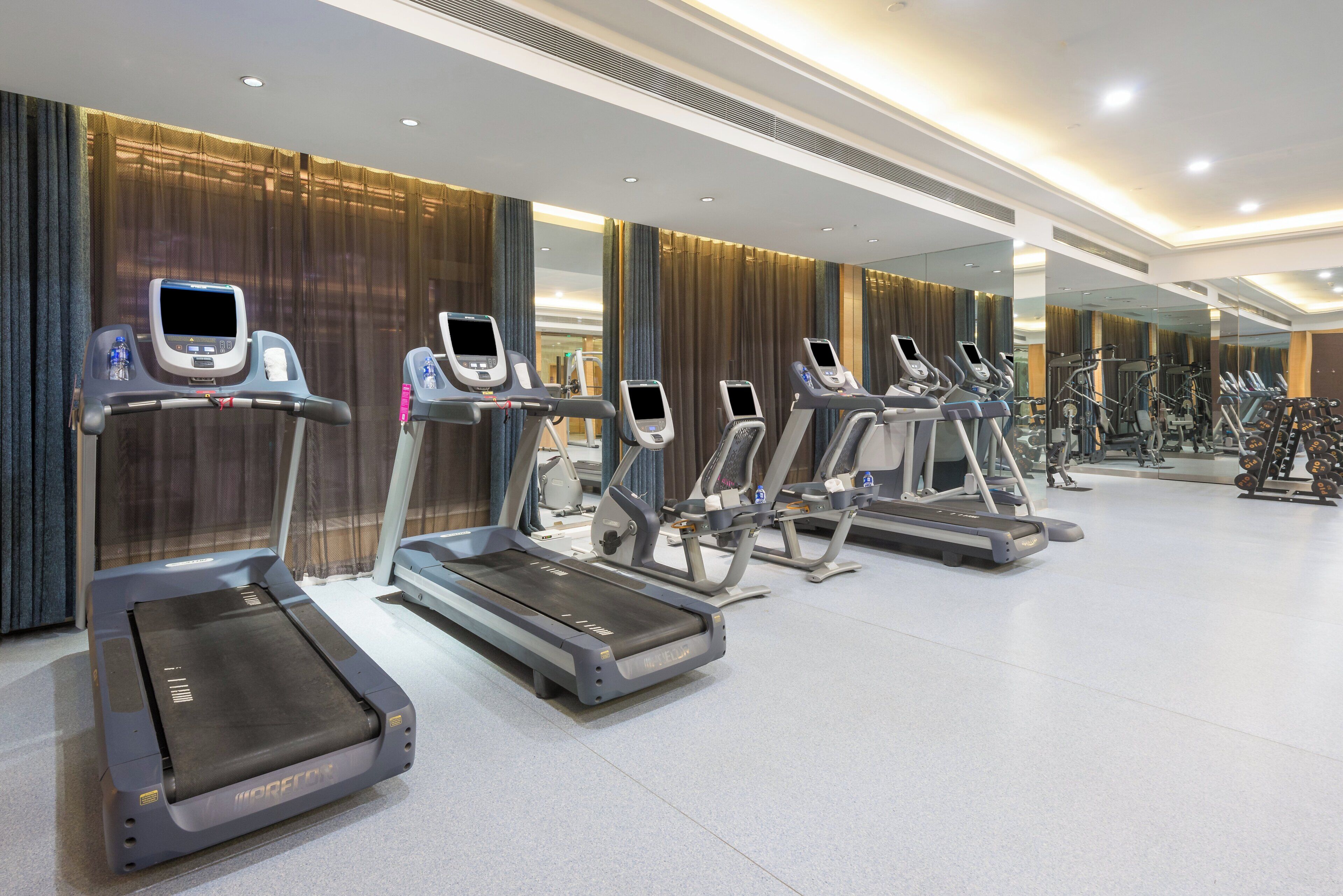 A gym with multiple treadmills, each equipped with a digital display.
