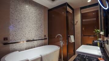 A modern bathroom with a freestanding bathtub, a glass-enclosed shower, and a vanity with a mirror.