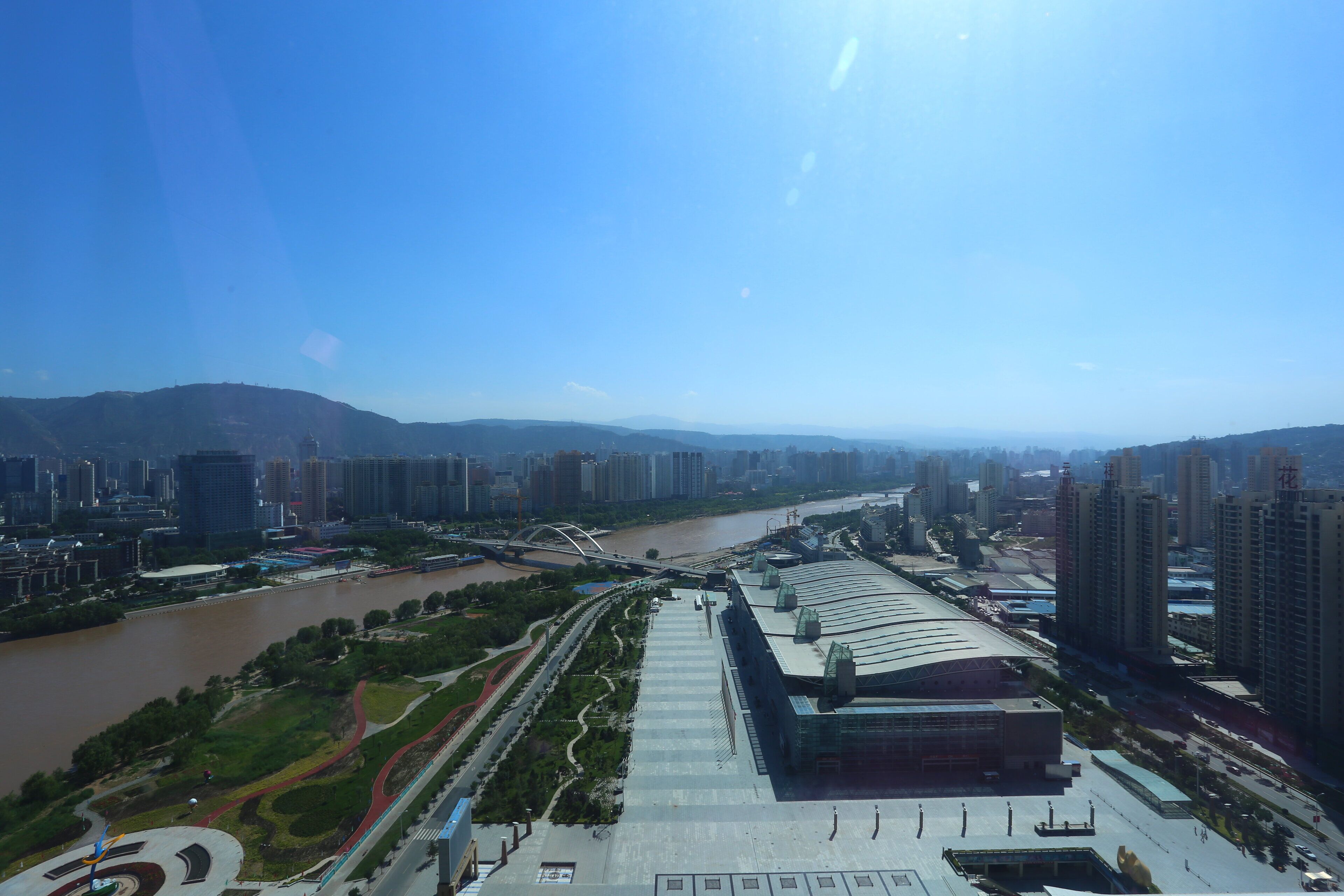 A modern building with a curved roof, surrounded by a river and high-rise buildings.