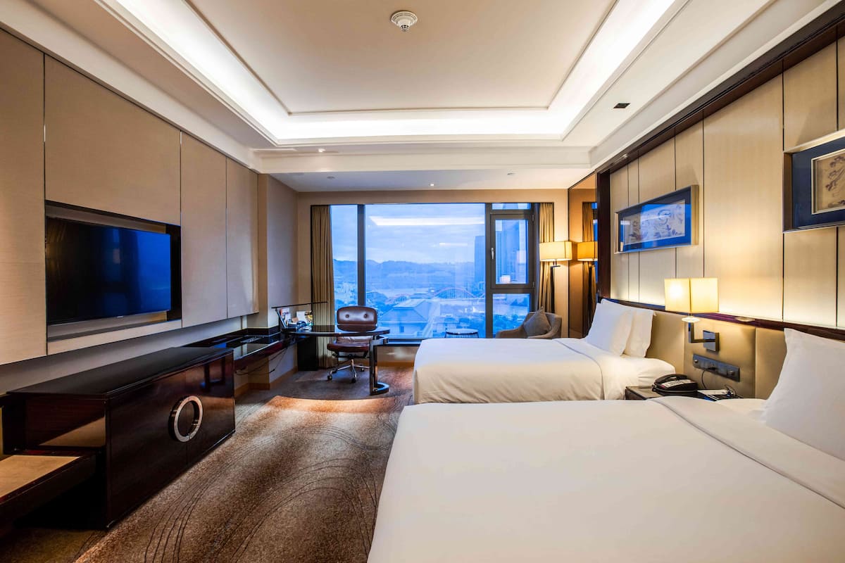 Une chambre d’hôtel avec un grand lit, un bureau avec une chaise, une télévision et une vue sur la ville.