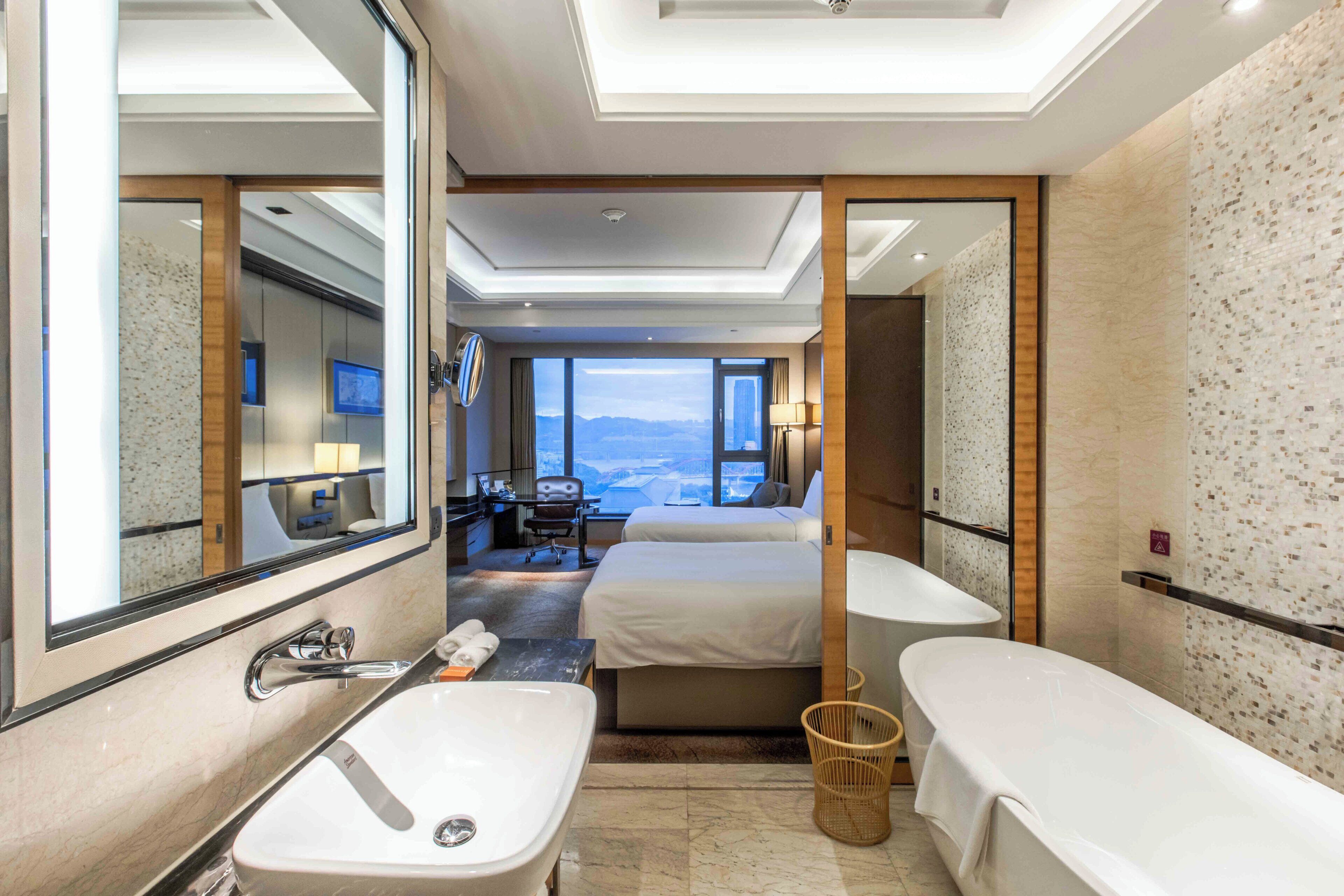 Habitación de hotel con una cama grande, un escritorio independiente, baño con bañera y vistas a la ciudad.