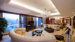 Un salon luxueux avec un grand canapé incurvé, un téléviseur et un lustre.