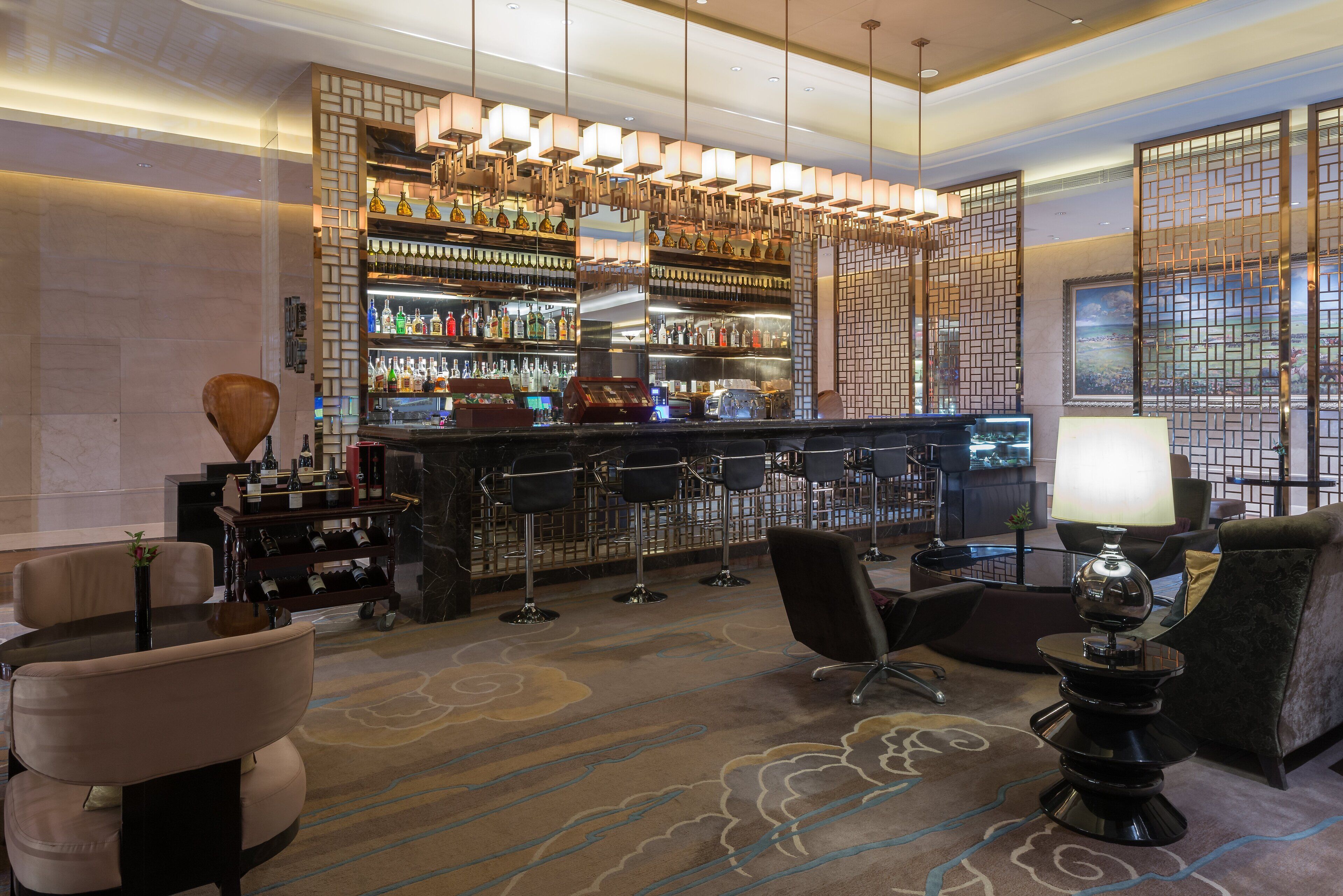 A bar area with a variety of liquor bottles, a bar counter, and seating arrangements.