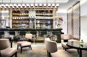 A bar area with multiple seating options, including bar stools and cushioned chairs, with a variety of bottles and glasses on shelves behind the bar. - Crowne Plaza Lanzhou by IHG (Lanzhou)
