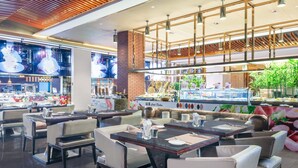 Un intérieur de restaurant moderne, avec plusieurs tables et chaises, un bar et un présentoir où sont exposés des produits alimentaires.