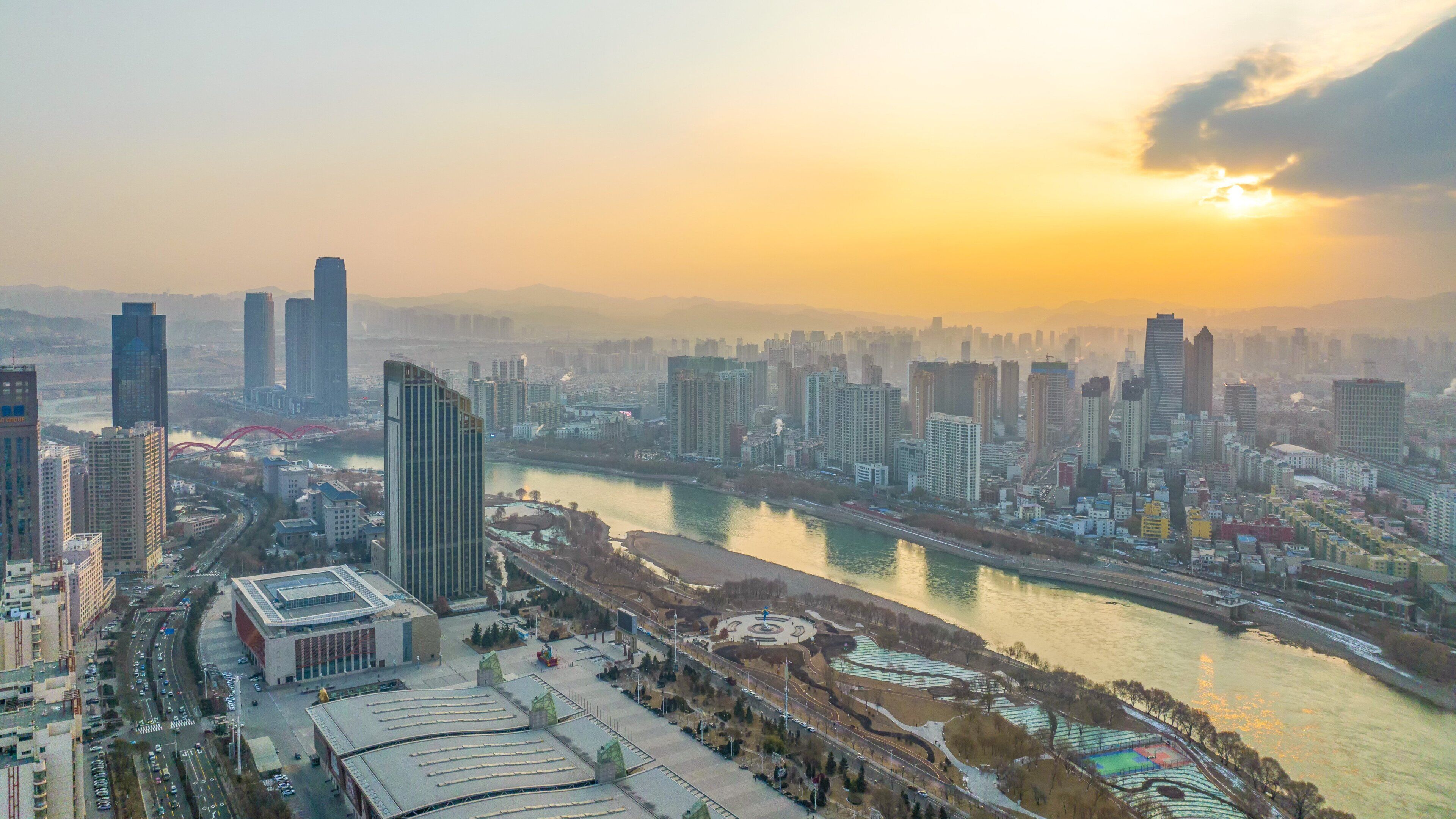 A cityscape with modern high-rise buildings, a river, and a bridge.