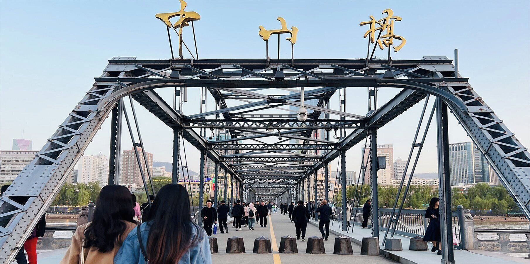 A pedestrian bridge with a metal framework and yellow decorative elements.