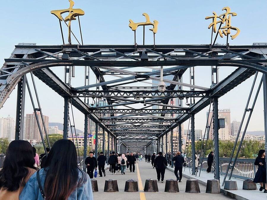 A pedestrian bridge with a metal framework and yellow decorative elements.