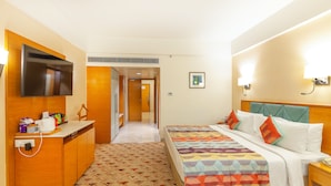 Habitación de hotel con cama, mesita de noche, televisor y escritorio con silla.