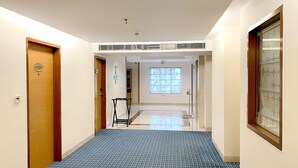 Un pasillo de hotel con piso de diseño azulado, puertas de madera y una ventana con motivos decorativos.