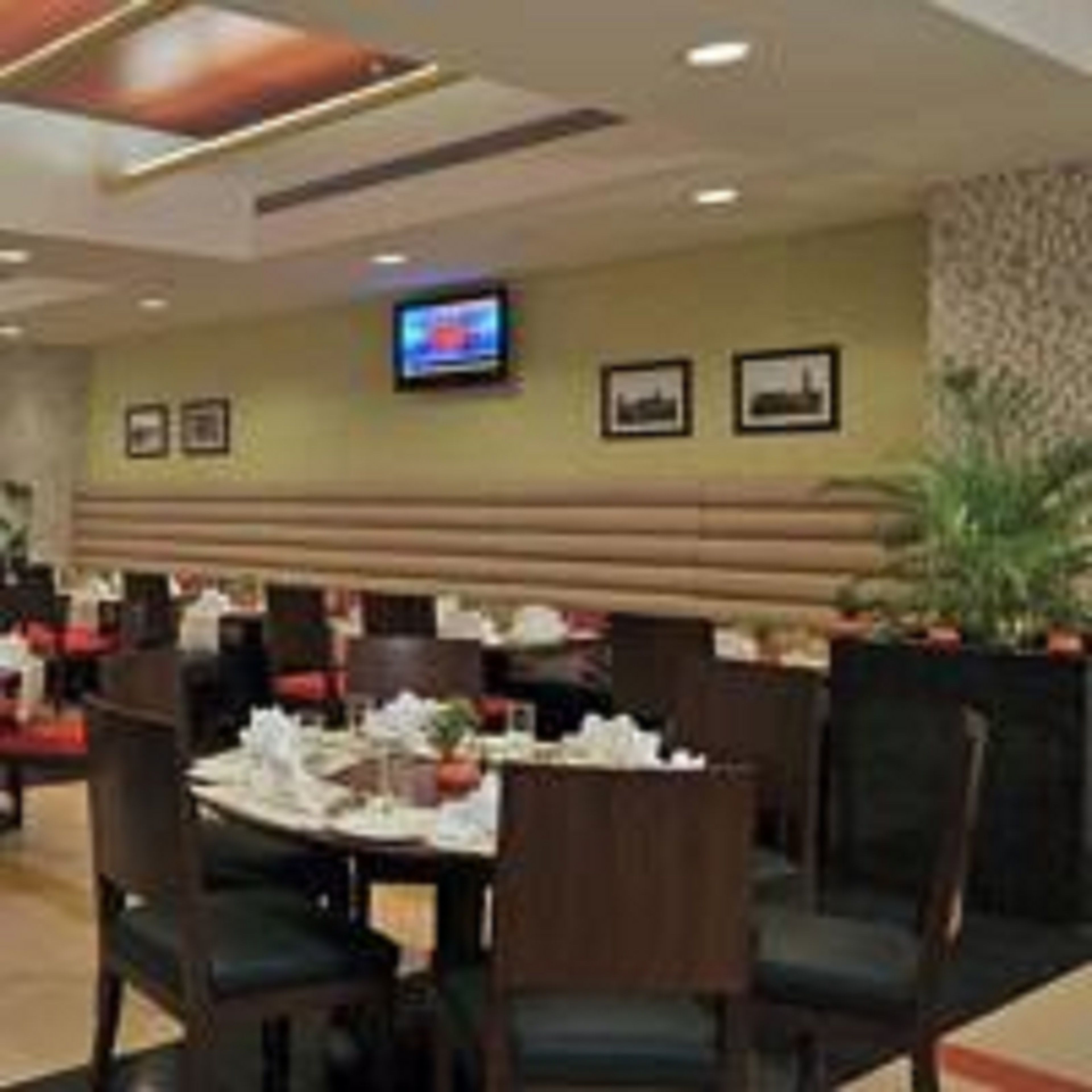 A restaurant with booths, a television mounted on the wall, and framed pictures.