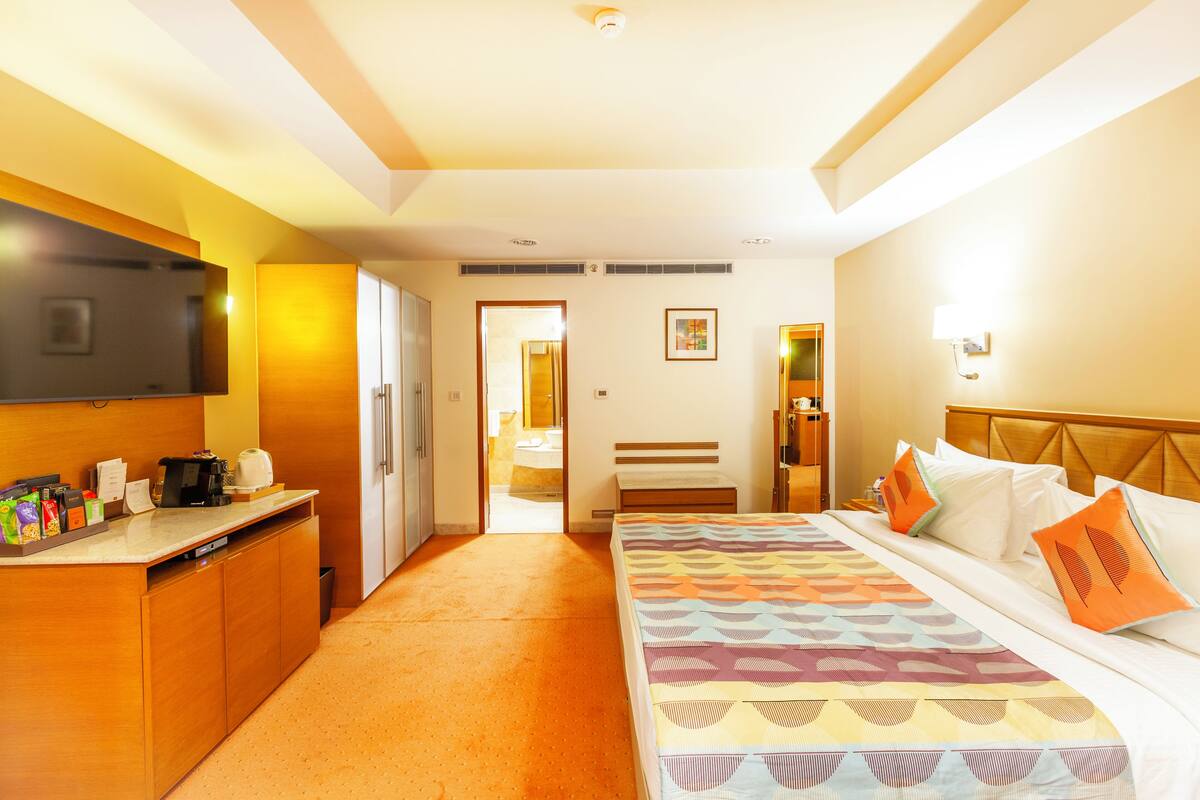 A hotel room with a bed, bedside table, and a desk with a coffee maker.