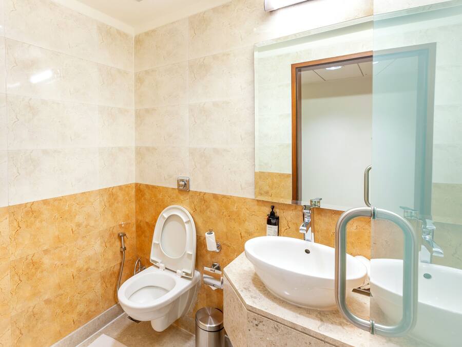 Un baño moderno con inodoro, lavamanos y espejo.