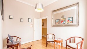 Una habitación amplia con suelo de madera, un espejo grande y varias obras de arte enmarcadas en la pared.