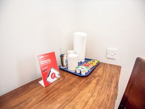 Habitación de hotel con una mesa de madera, un cartel que promociona la aplicación OYO, artículos de aseo y una bandeja con varios objetos.