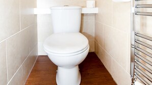 Une petite salle de bain moderne avec des toilettes blanches, un plancher en bois et un porte-serviettes.