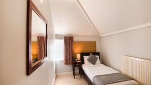 Une chambre d’hôtel avec un lit, une table de chevet, une lampe et un miroir.