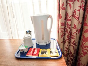 Una bandeja con una tetera, un termo, una taza y dos paquetes de té Twinings Everyday sobre una mesa de madera.