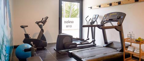 Un gimnasio en casa con cinta de correr, bicicleta estática y pelota de ejercicios.