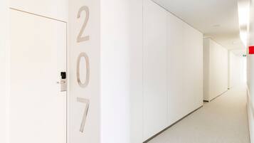 A hallway with white walls and doors, featuring the numbers 207 on the left wall.