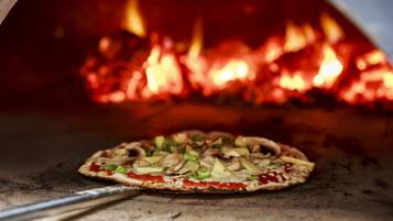Pizza dentro de um forno a lenha, com chamas visíveis.