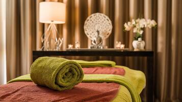 Experience a serene atmosphere in this spa room, featuring a massage table, decorative lamp, and a vase with fresh flowers.
