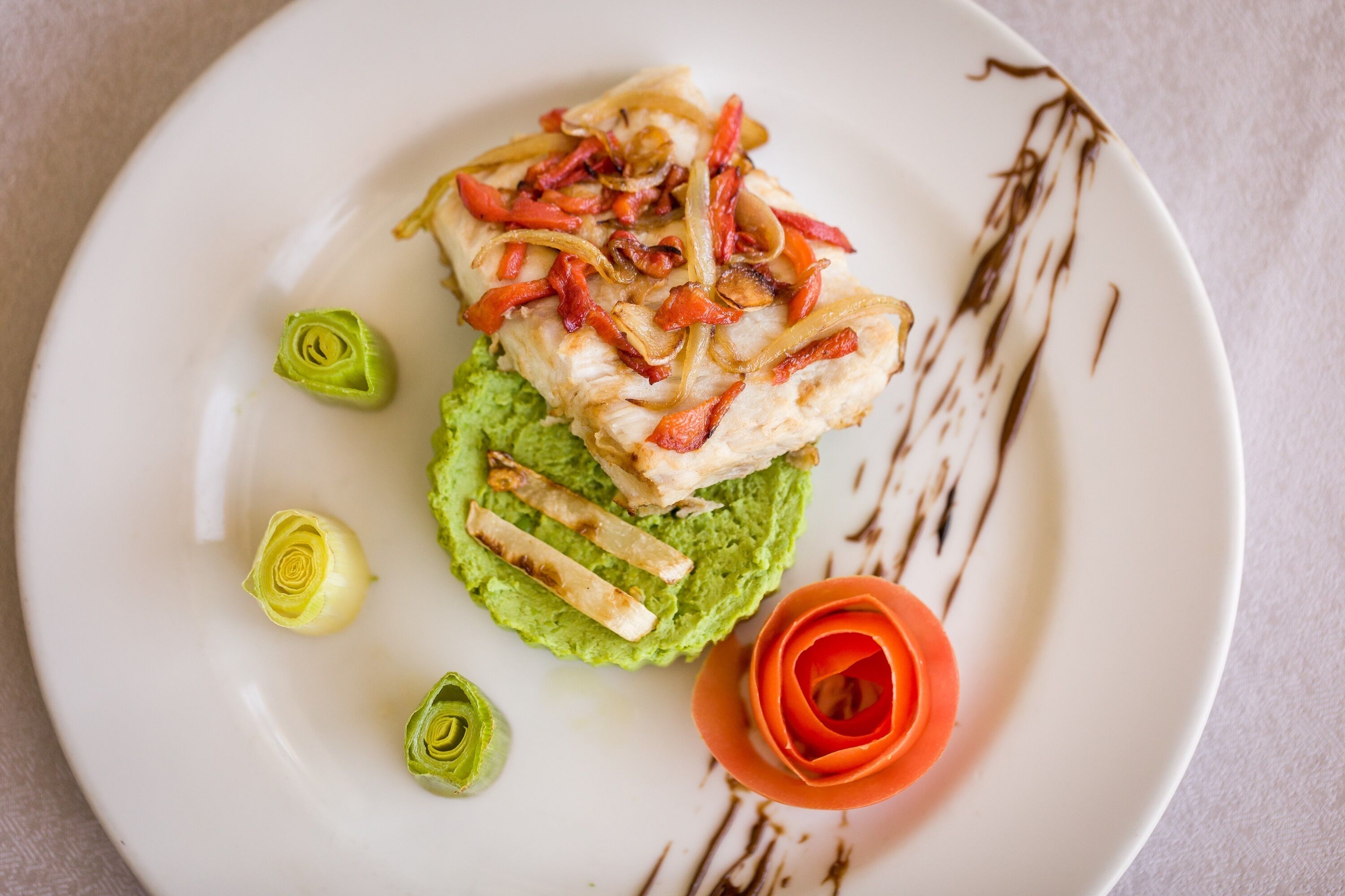 Ein Teller mit gegrilltem Hähnchen, Avocado-Scheiben und dekorativen Elementen.