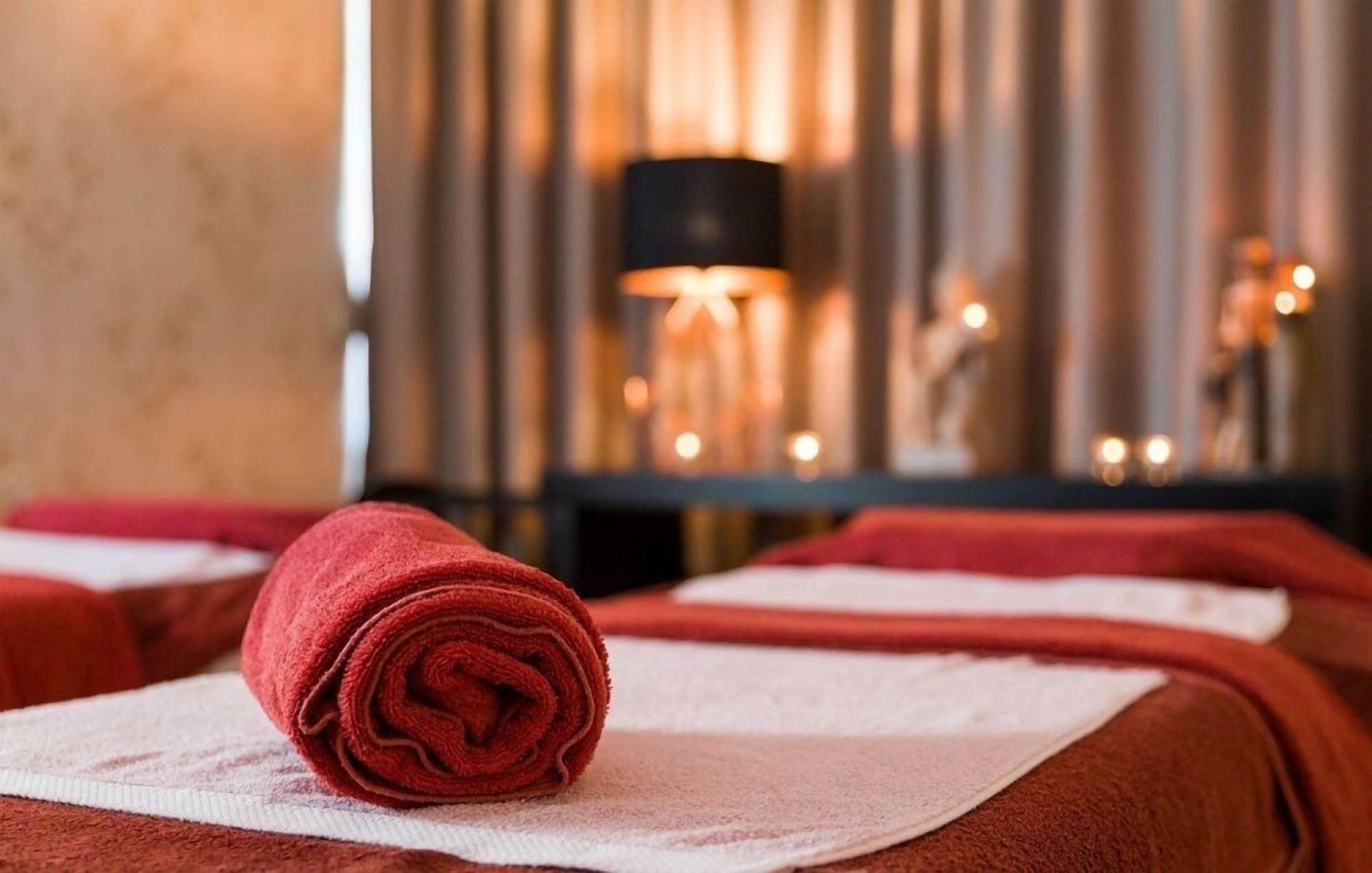 A neatly arranged massage area with towels and a lamp in the background.