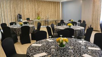 A conference room with round tables, black chairs, and floral centerpieces.