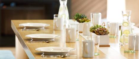 A neatly arranged dining table with plates, cutlery, glasses, and a pitcher of water.